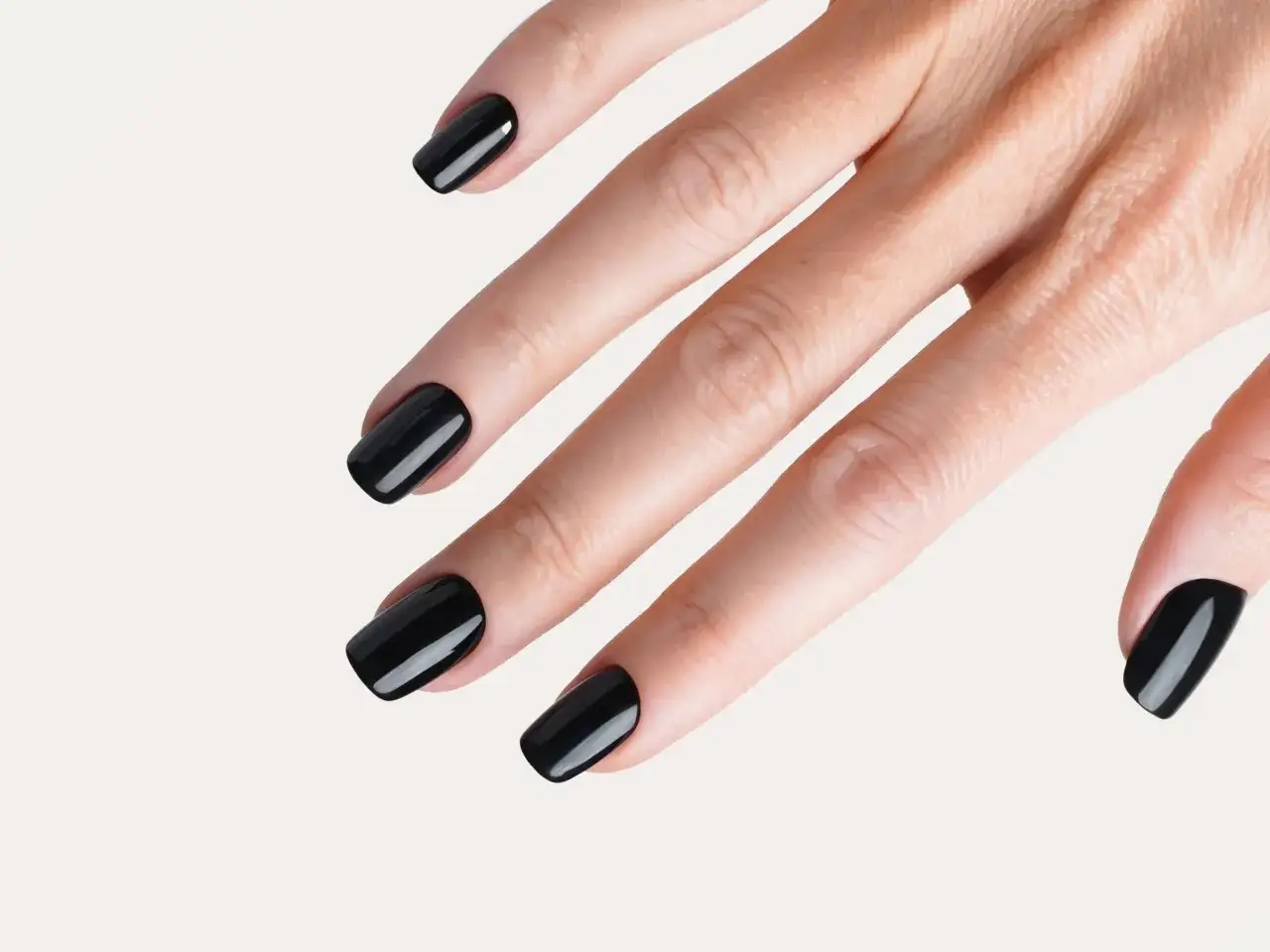 Une main aux ongles vernis d'un noir profond, une manucure noir élégante et sophistiquée.