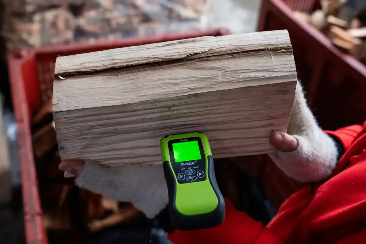 Mesure de l'humidité d'un bois de chauffage trop vieux avec un humidimètre. Le bois semble sec, mais la mesure le confirmera.