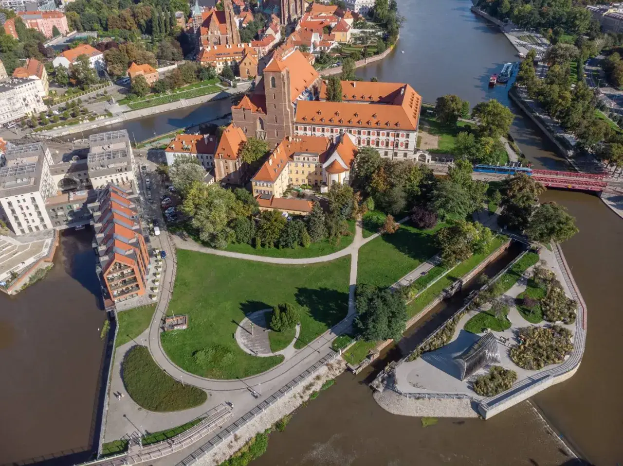 Widok z lotu ptaka na Ostrów Tumski, gdzie Odra, czyli jaka rzeka płynie przez Wrocław, otacza zabytkowe budowle i zielone tereny.