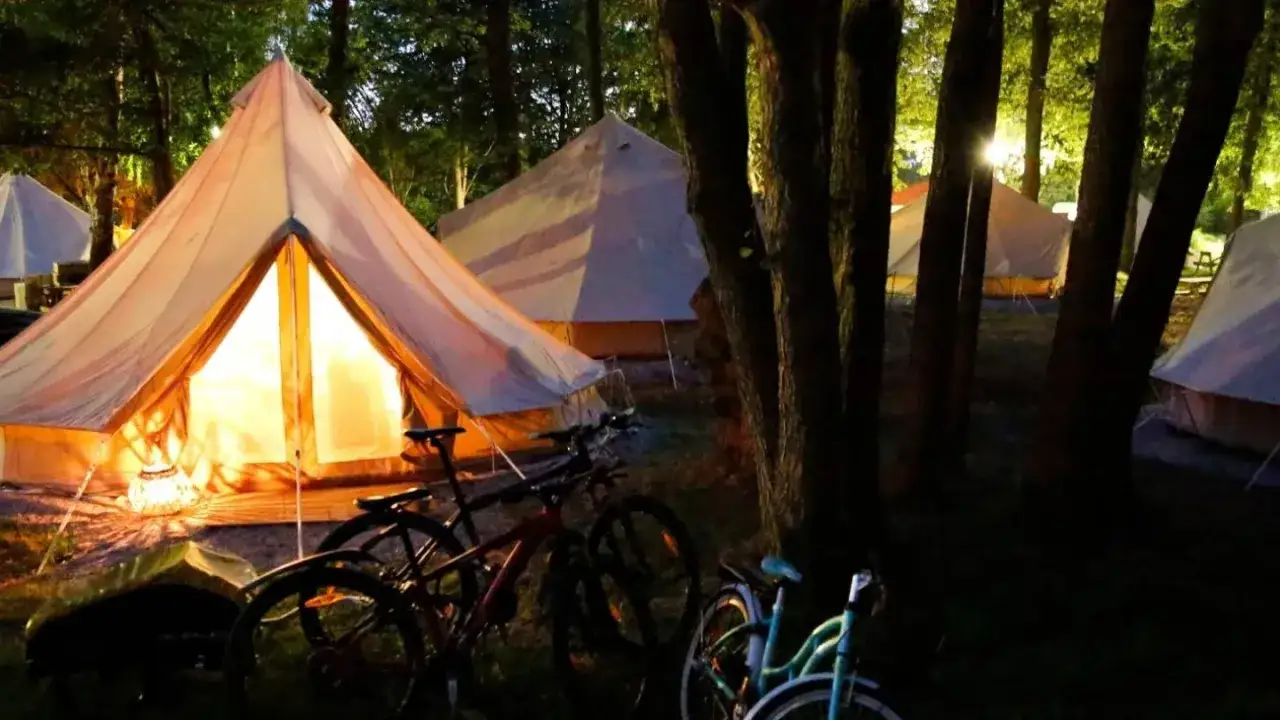 Skönstavik: glampingtält lyser upp skogen på kvällen, med cyklar redo för äventyr.