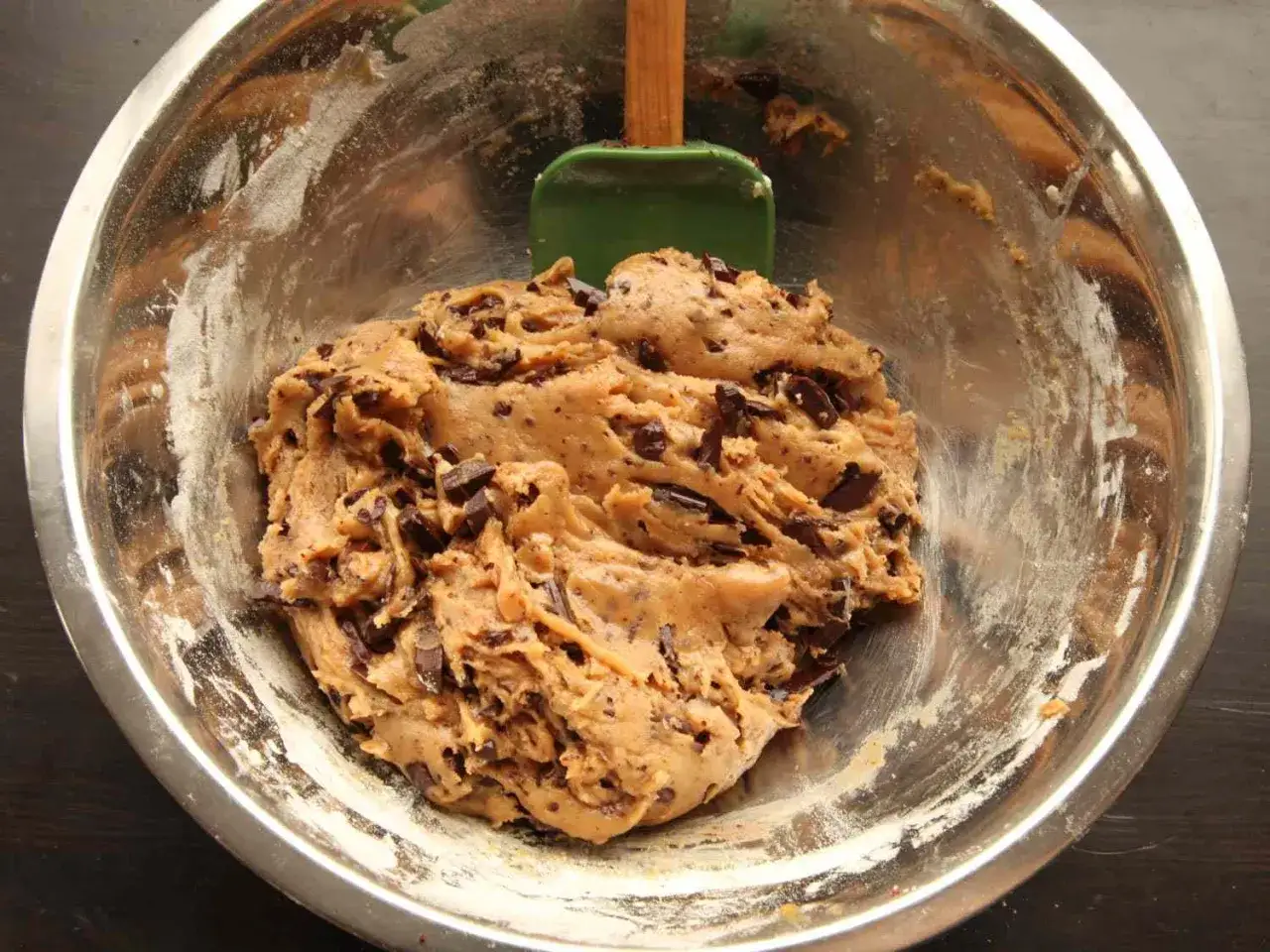 Schokoladenkeksteig in einer Schüssel, bereit für das cookies rezept. Ein grüner Teigschaber liegt daneben.