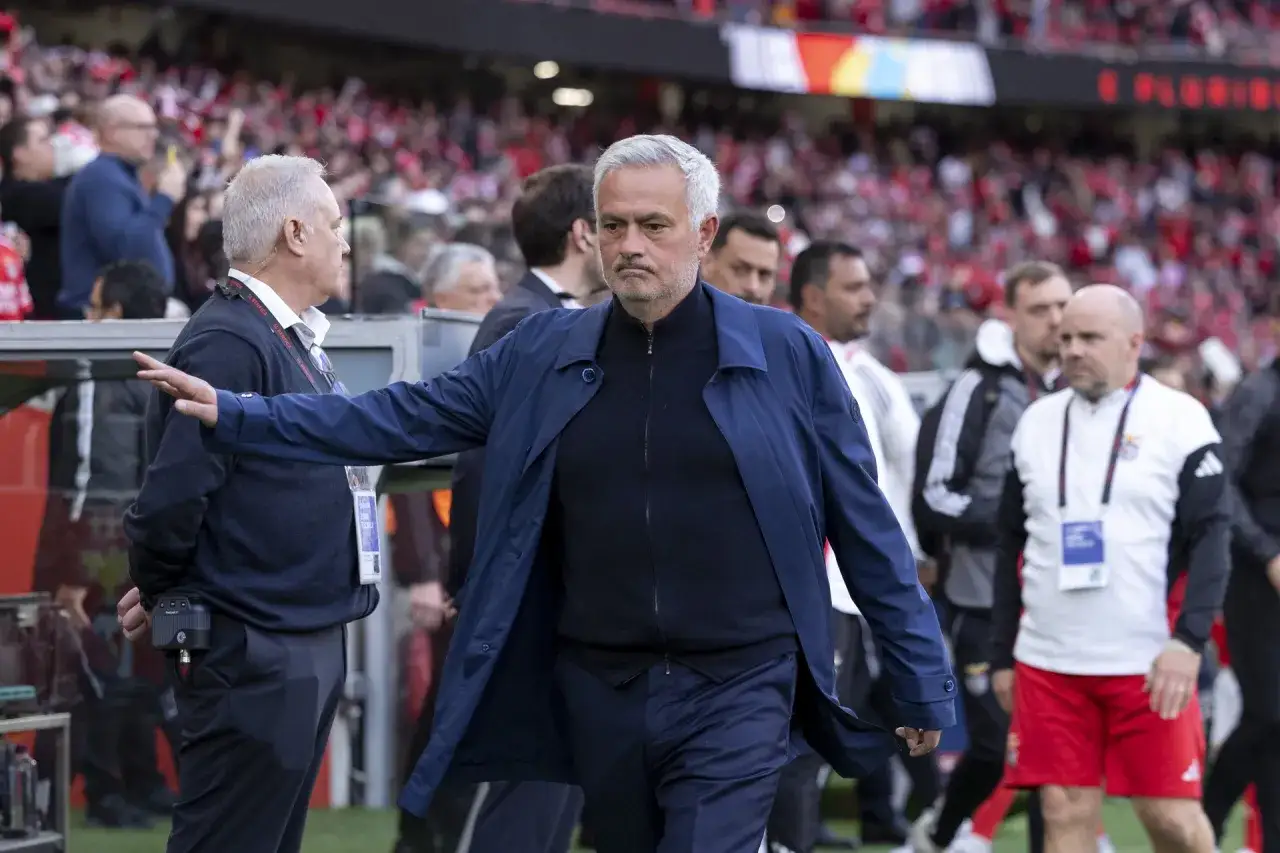 Jose Mourinho, znany trener Realu, idzie po boisku w otoczeniu innych osób.