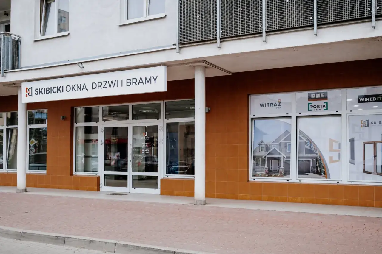 Elegancki salon okien i drzwi z witrynami prezentującymi domy i produkty.