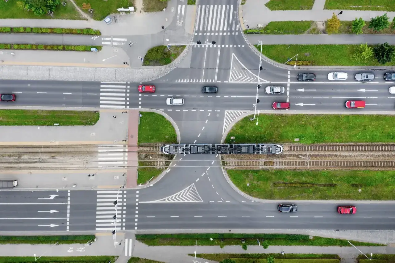 Widok z lotu ptaka na skrzyżowanie z tramwajem i samochodami. Uważaj na parkowanie w obrębie skrzyżowania, by nie blokować ruchu.