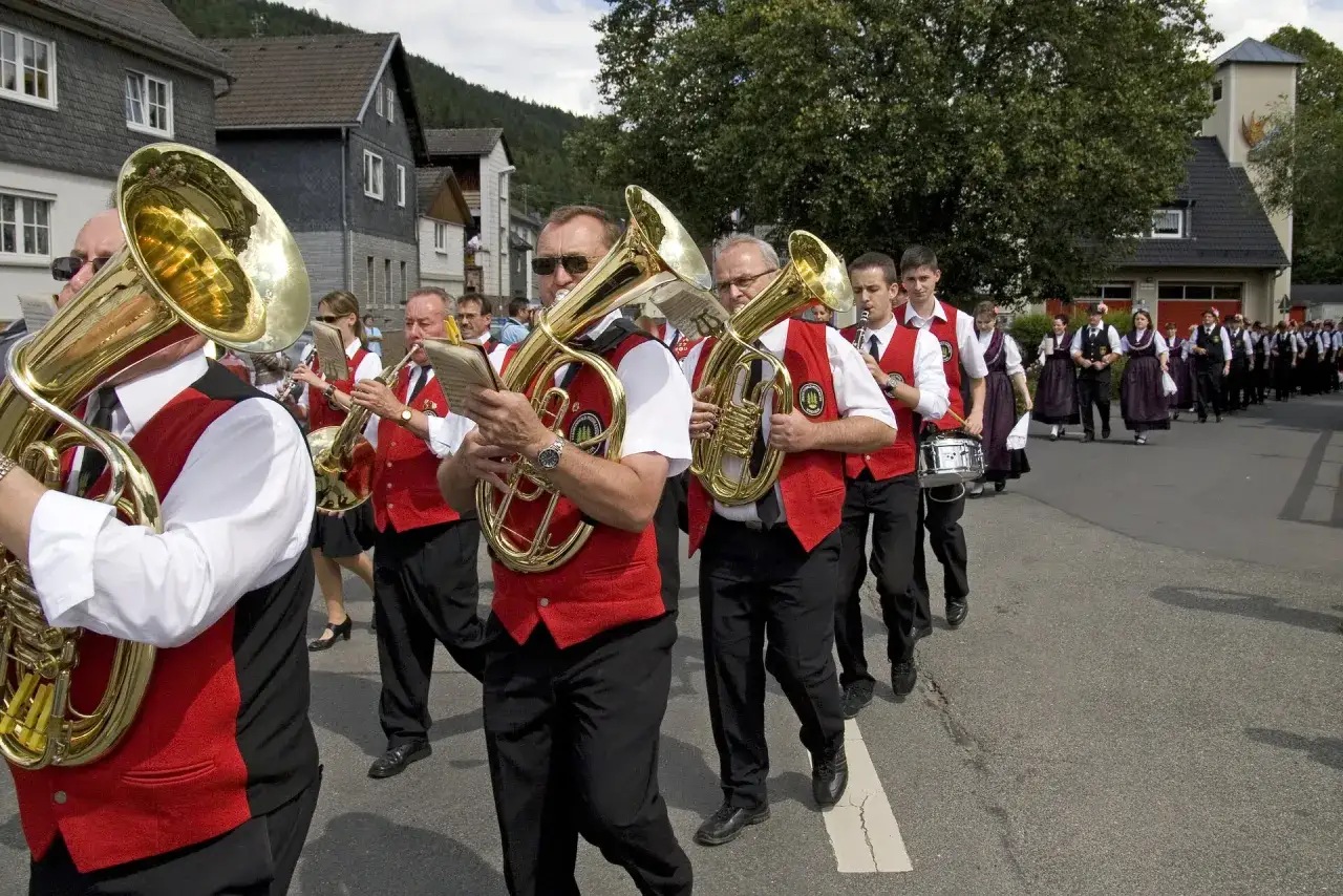 Musikkapelle marschiert bei bayrischer Kirchweih. Blaskapelle in roten Westen spielt auf der Straße.