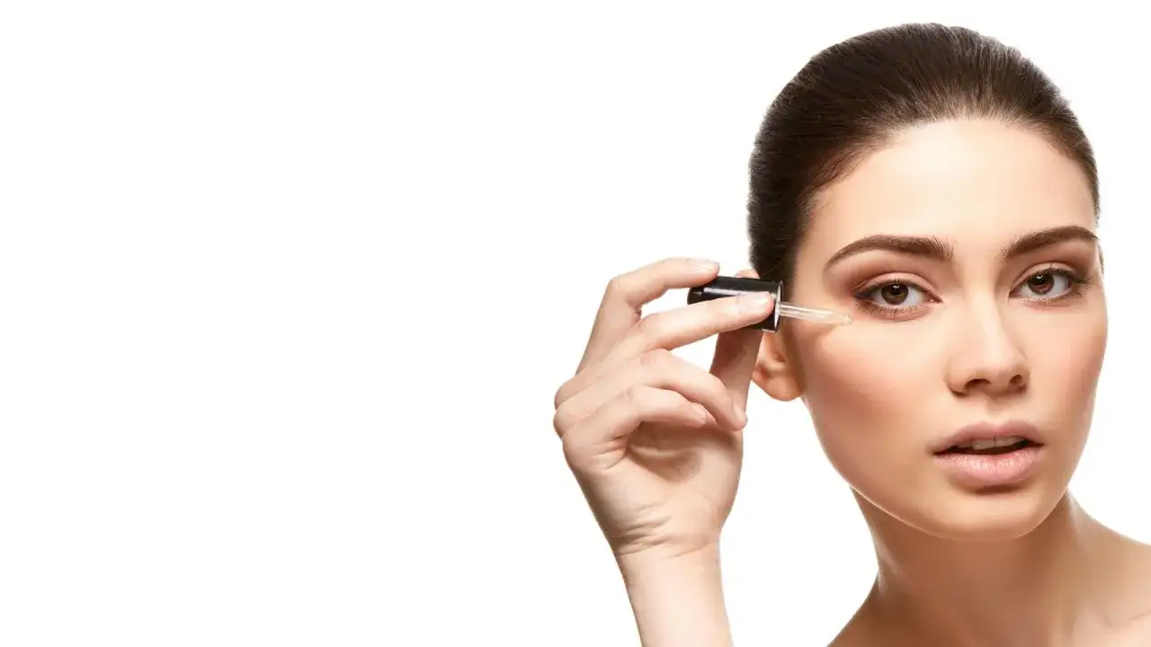 Kobieta aplikuje podoserum pod oczy za pomocą pipetki. Delikatna pielęgnacja dla promiennej skóry.