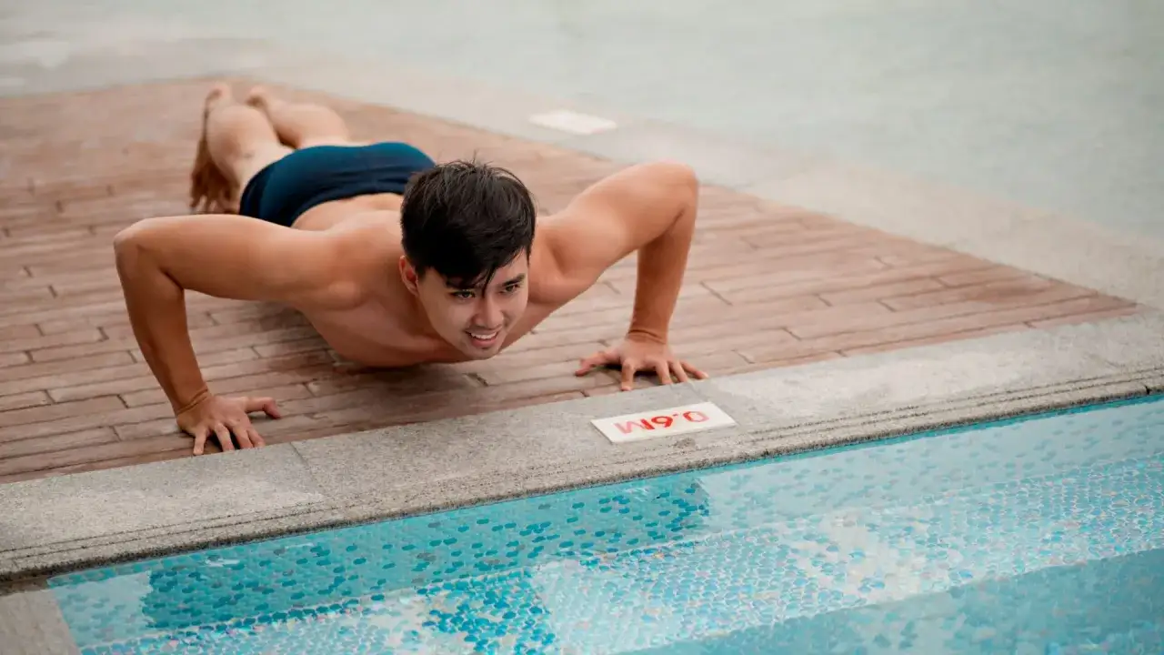 Swimmer performing push-ups by the pool, showcasing effective dryland workouts for enhanced performance.