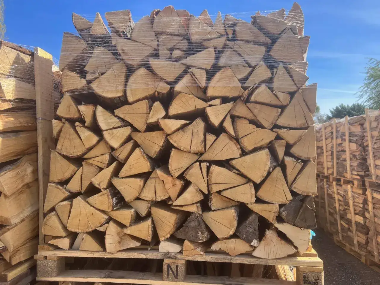 Un poids stère de bois de chauffage, bien rangé sur une palette et emballé sous film plastique, prêt pour l'hiver.