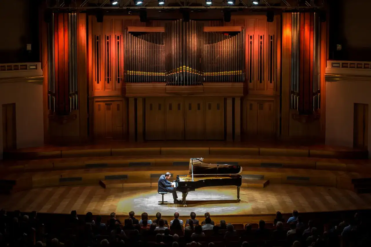 Un pianiste interpr&egrave;te une musique classique piano connue devant un orgue imposant. L'ambiance est solennelle.