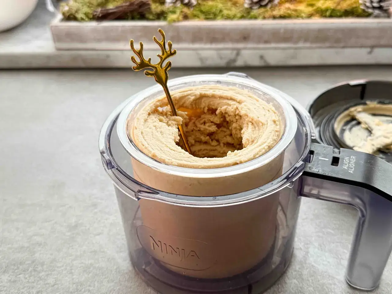Ein goldener Hirsch-Löffel steckt in cremigem, hellbraunem Eis in einer Ninja-Eismaschine. Perfekt für ein Bier-Eis-Dessert!