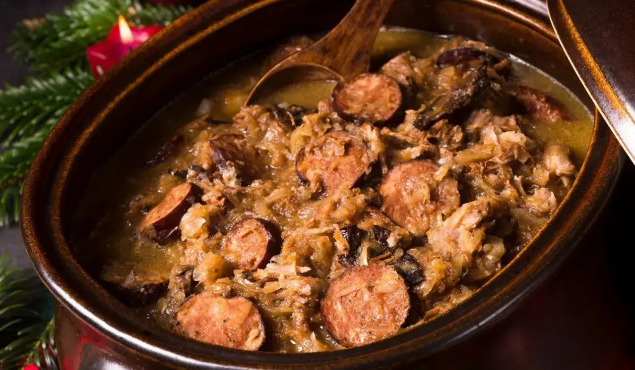 Gęsty, aromatyczny bigos w glinianym naczyniu, z widocznymi kawałkami kiełbasy i kapusty. Idealne przyprawy do bigosu podkreślają jego świąteczny charakter.