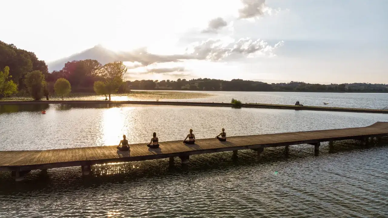 Persone in meditazione su un pontile al tramonto sul lago di Chiusi.