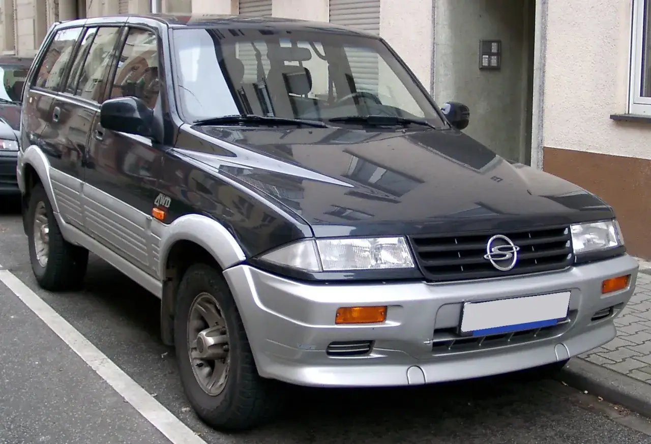Ciemnoszary Daewoo Musso 4WD z srebrnymi elementami, zaparkowany na ulicy.