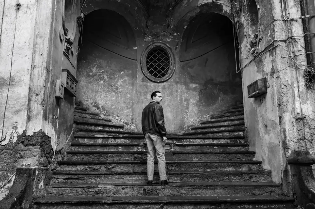 Un uomo si volta su una scala di pietra grezza. Questo luogo evoca l'atmosfera de