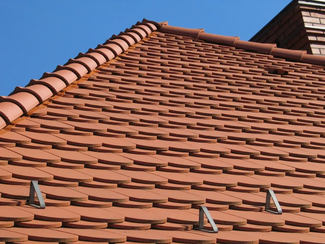 Nowy dach z dach&oacute;wki ceramicznej, ułożonej w charakterystyczny wz&oacute;r łuski, lśni w słońcu.