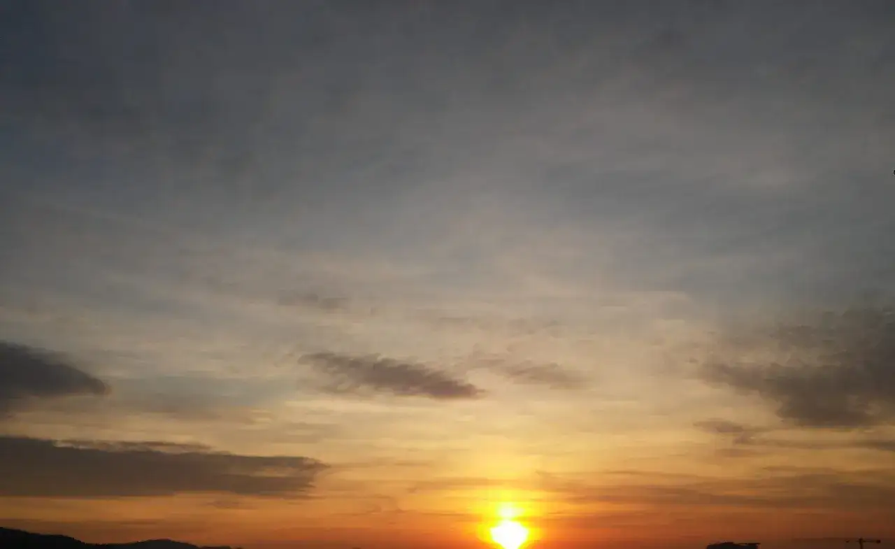 Tramonto con nuvole che suggeriscono una possibile temporale analisi. Il sole illumina l'orizzonte con colori caldi.