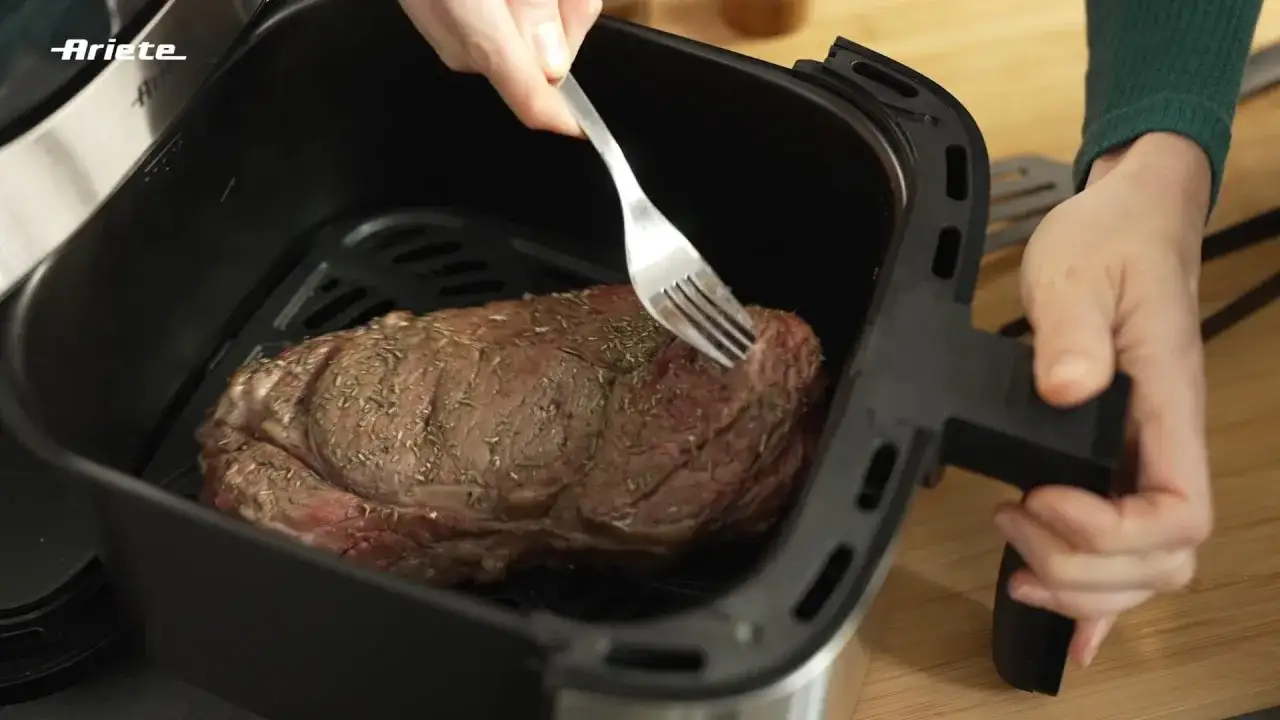 Una succulenta tagliata in friggitrice ad aria, condita con erbe aromatiche, pronta per essere cucinata.