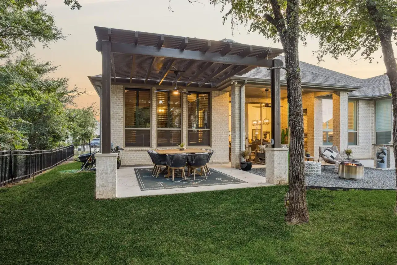 Table et chaises sous une pergola, parfaites pour la décoration véranda extérieur. Un feu de camp et des sièges invitent à la détente.