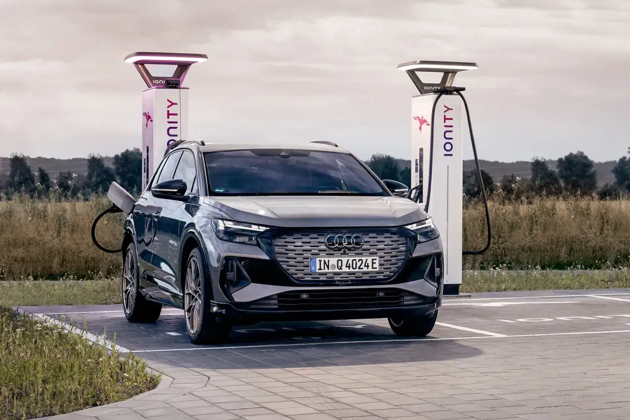 En m&ouml;rkgr&aring; Audi Q4 e-tron laddas vid en IONITY-station. En perfekt begagnad elbil f&ouml;r framtiden.
