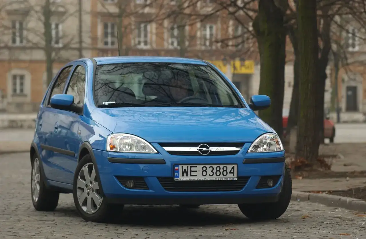 Niebieski Opel Corsa C z przodu, z widocznymi żarówkami przednimi.