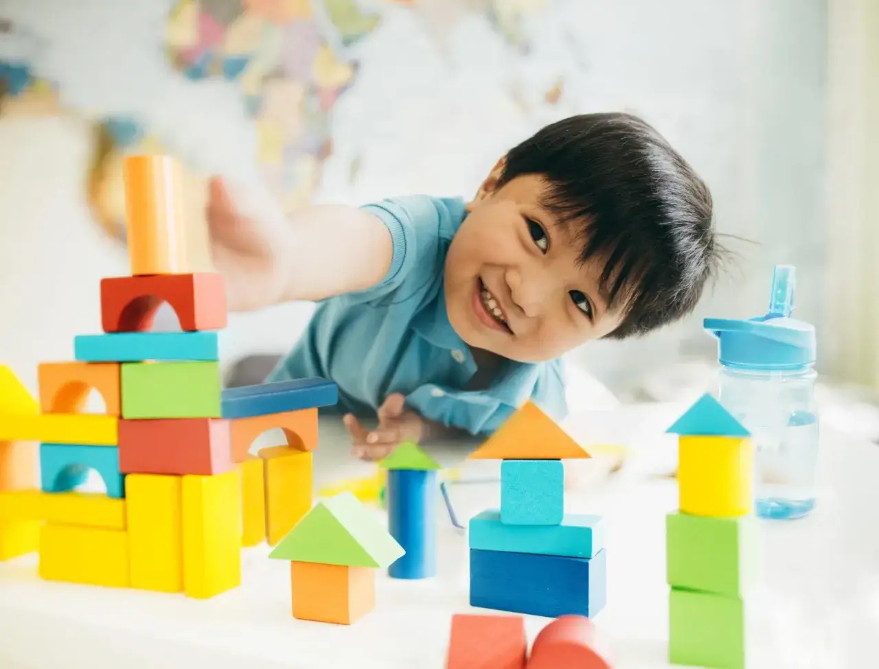 Ni&ntilde;o de 2 a&ntilde;os sonr&iacute;e jugando con bloques de colores. Las pantallas de los ni&ntilde;os de 2 a&ntilde;os son una herramienta para el aprendizaje.