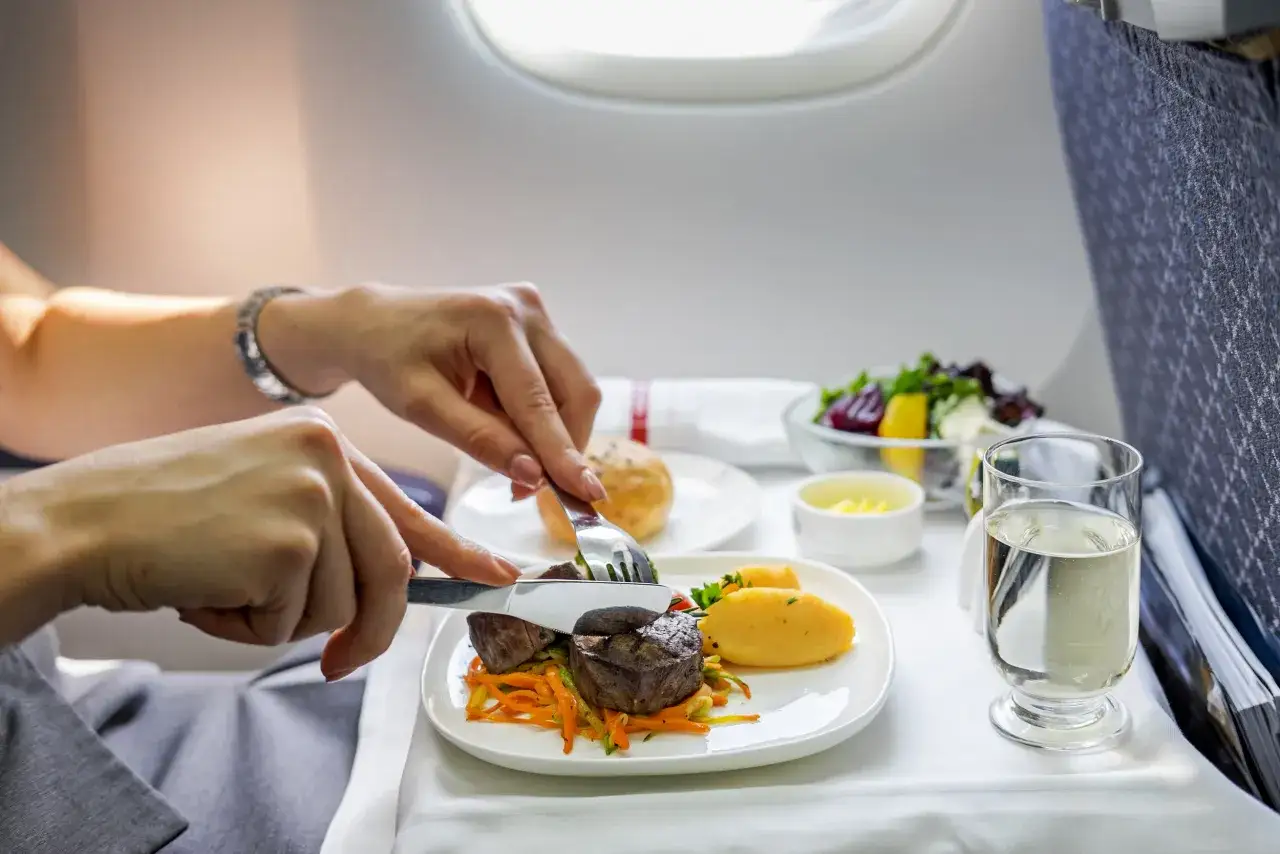Genussvolles tuifly essen: Ein zartes Steak mit Kartoffelp&uuml;ree und Gem&uuml;se, dazu ein Salat und ein Glas Wasser.