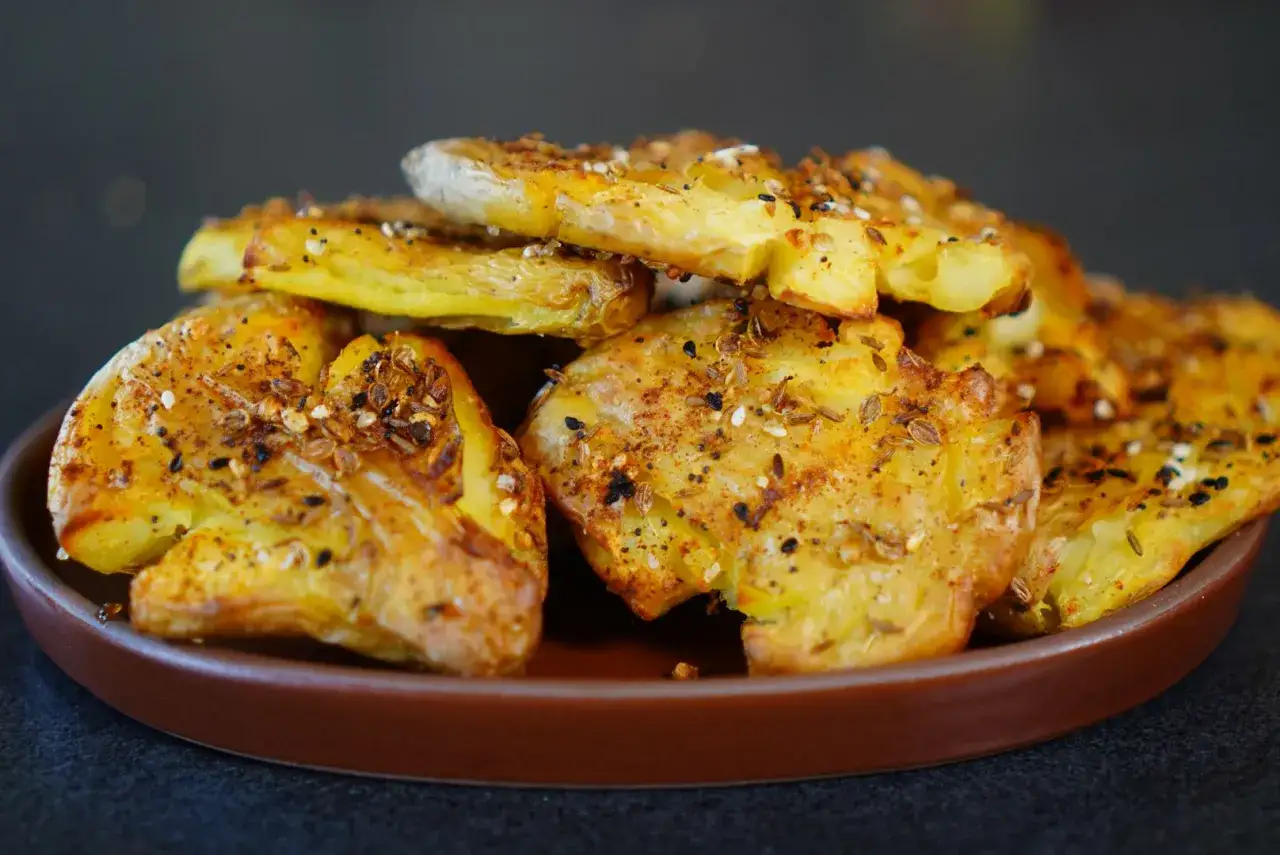 Galettes de pomme de terre croustillantes, assaisonn&eacute;es d'&eacute;pices et de graines, servies sur une assiette marron.