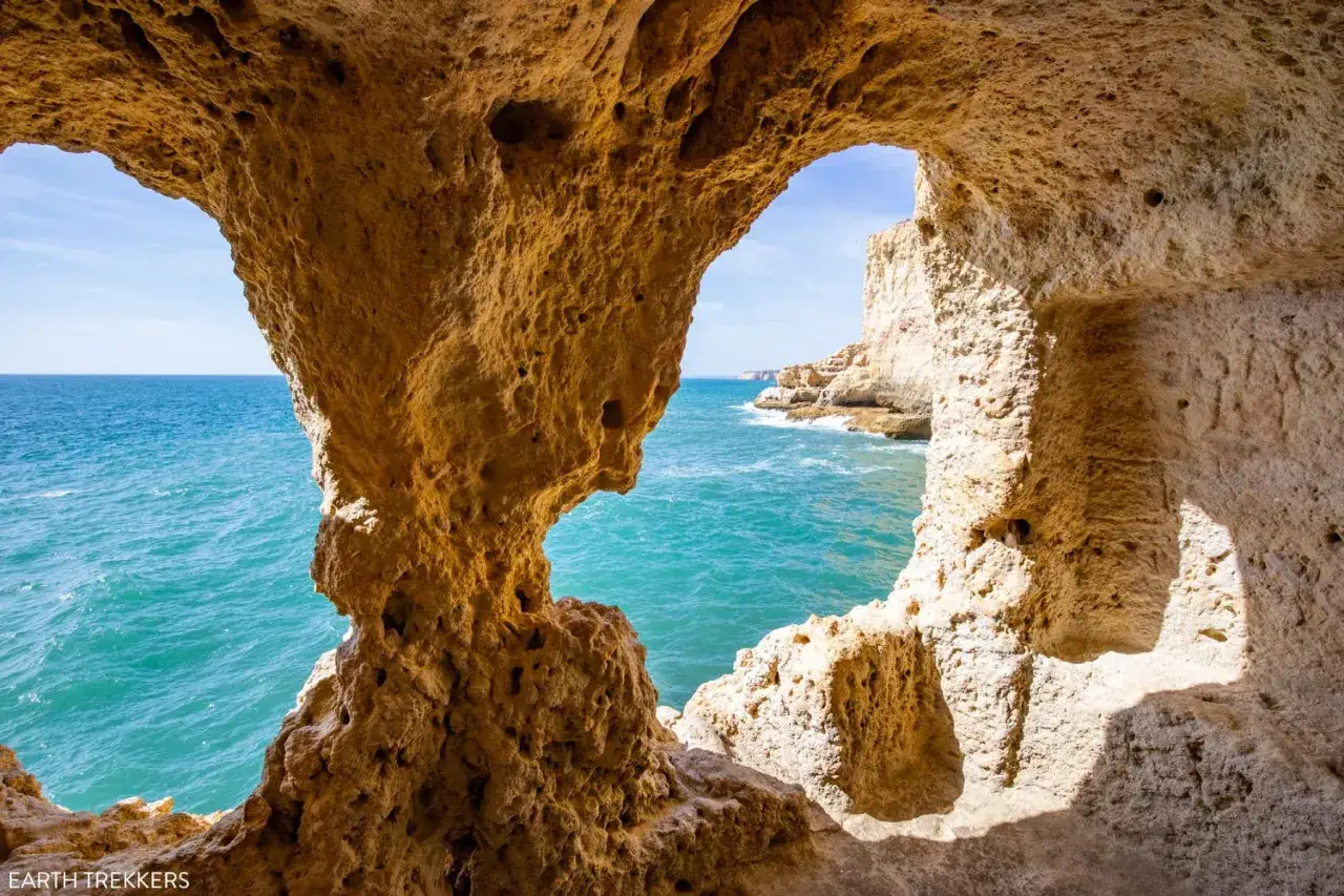 Blick durch eine H&ouml;hle auf das t&uuml;rkisfarbene Meer an der Algarve. Das Wetter in Portugal im Oktober ist perfekt f&uuml;r solche Ausblicke.
