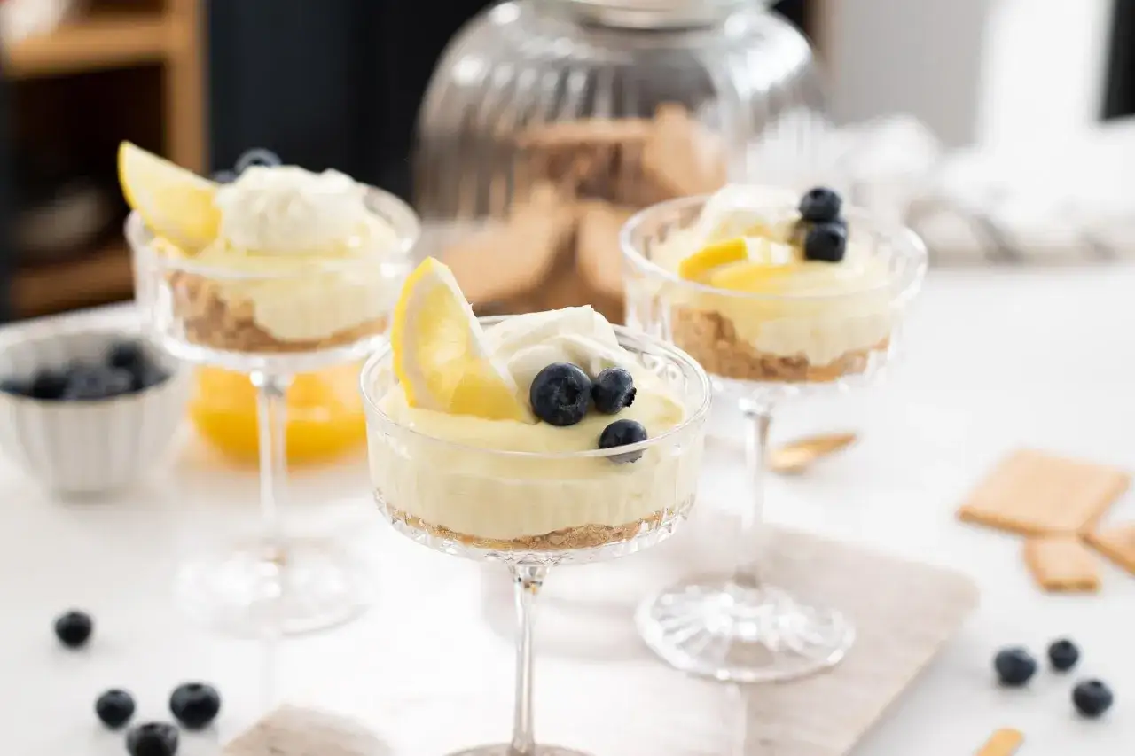 Deliziosa mousse al limone in coppette di vetro, guarnita con limone e mirtilli. Perfetta per un dessert fresco.