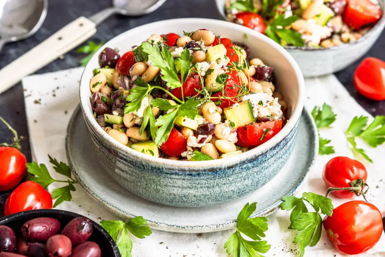 Ein bunter griechischer Bohnensalat mit Tomaten, Gurken, Oliven und Feta, garniert mit frischer Petersilie.