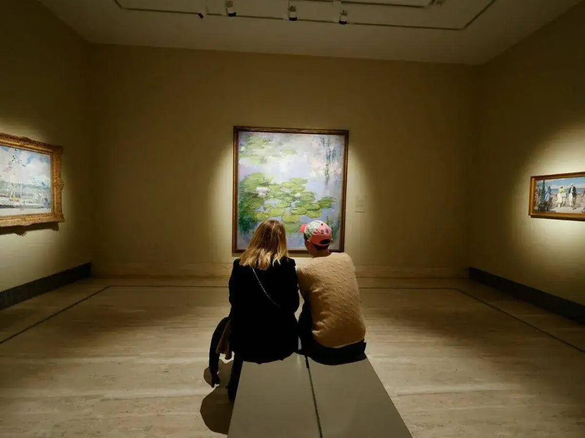 Dos personas contemplan un cuadro de nen&uacute;fares en la noche de los museos.