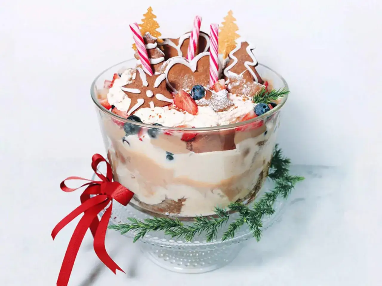 En härlig dessert julafton i en glasskål, dekorerad med pepparkakor, bär och polkagrisar.
