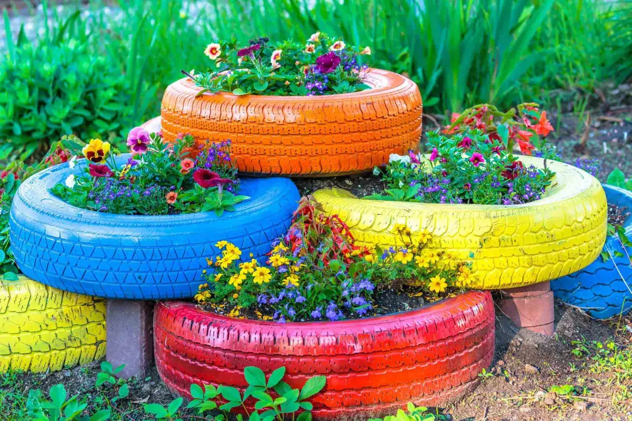 Un jardin punk coloré avec des pneus recyclés en pots de fleurs vibrants, débordant de fleurs vives.