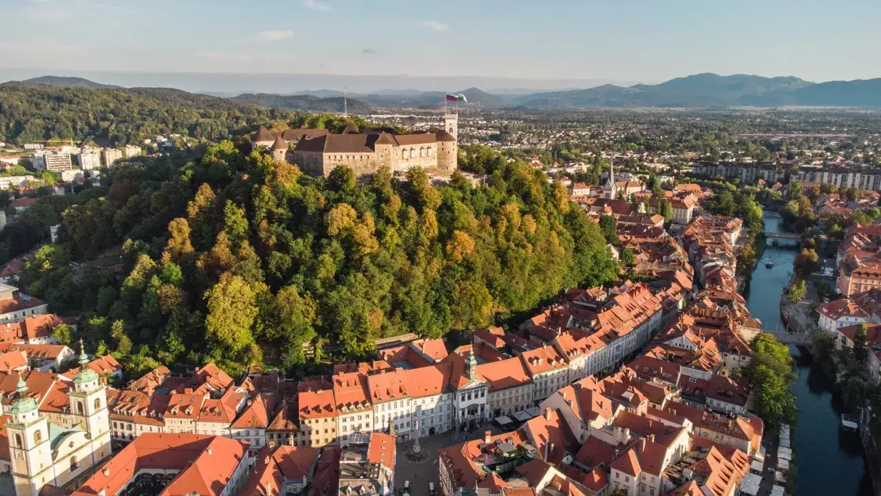 Widok na zamek na wzgórzu i rzekę przepływającą przez miasto. To wspaniałe miejsce, co warto zobaczyć w Słowenii!