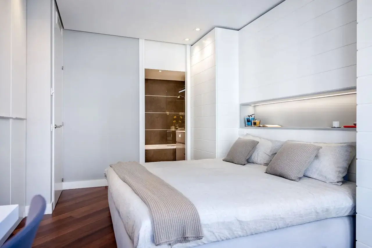 Habitaci&oacute;n moderna con cama, ba&ntilde;o visible y detalles para decorar habitaci&oacute;n estudio.