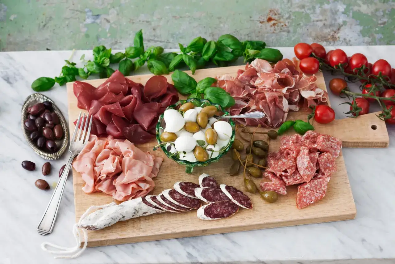En vacker charkbricka med salami, prosciutto, bresaola, mozzarella, oliver, kapris och tomater. Perfekt f&ouml;r en festlig sammankomst. H&auml;r &auml;r n&aring;gra charkbricka tips!