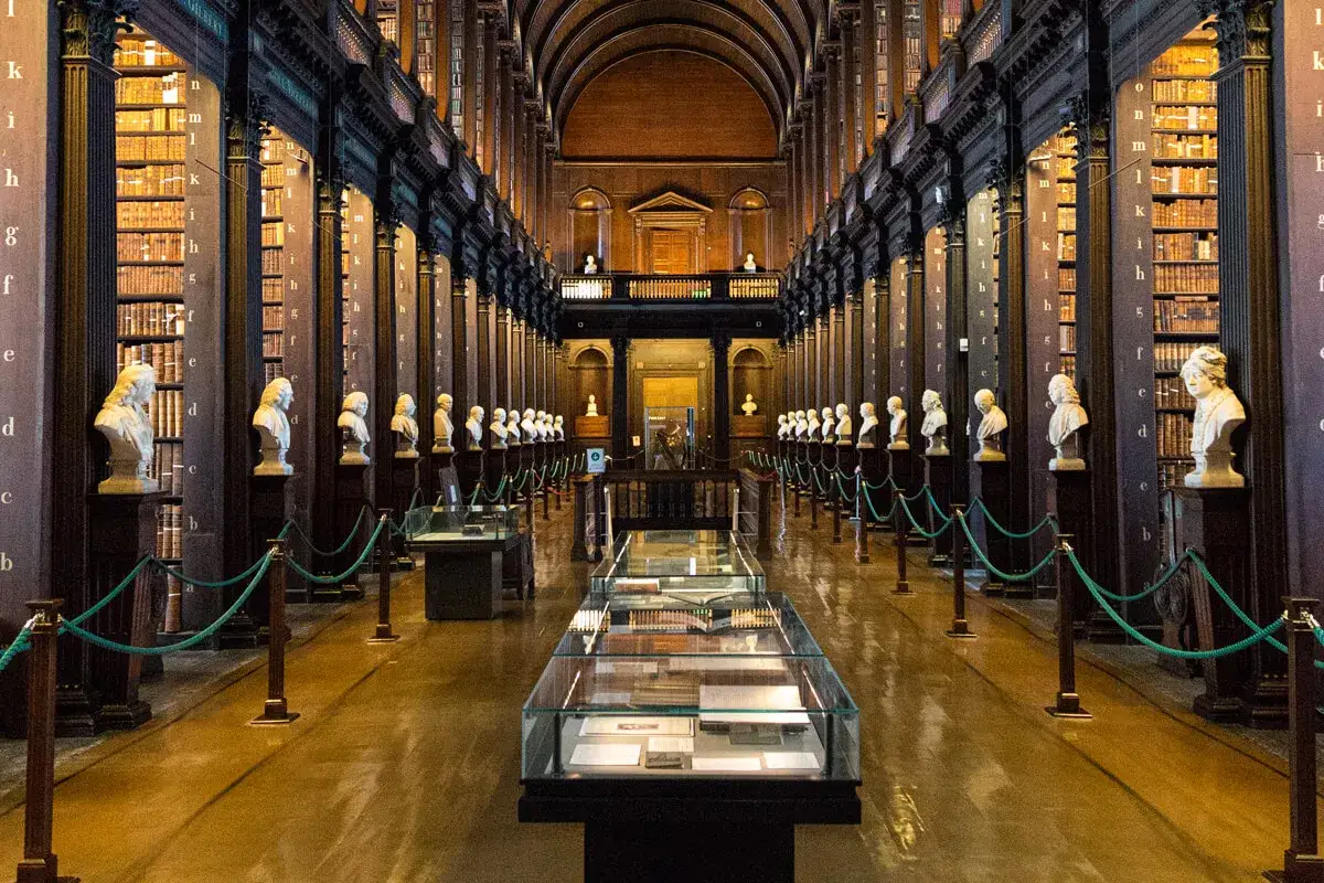 La Gran Sala de la Biblioteca del Trinity College, donde se exhibe el **libro de Kells**, con bustos de m&aacute;rmol y estanter&iacute;as repletas de libros antiguos.