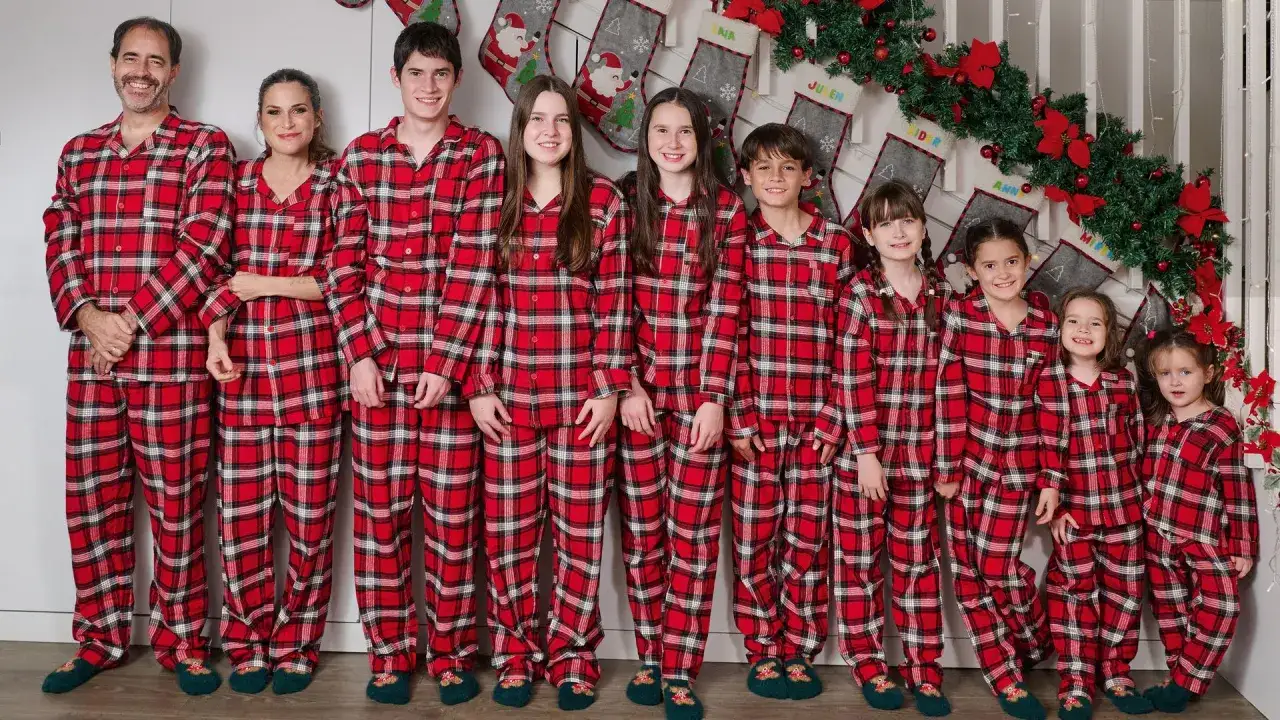 Familia reunida en pijamas a cuadros rojos, unida por frases de familia y el espíritu navideño.