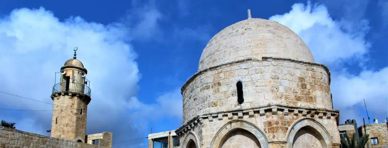 Kamienna kopuła i minaret pod błękitnym niebem. Tak wygląda Jerozolima, miasto o bogatej historii.