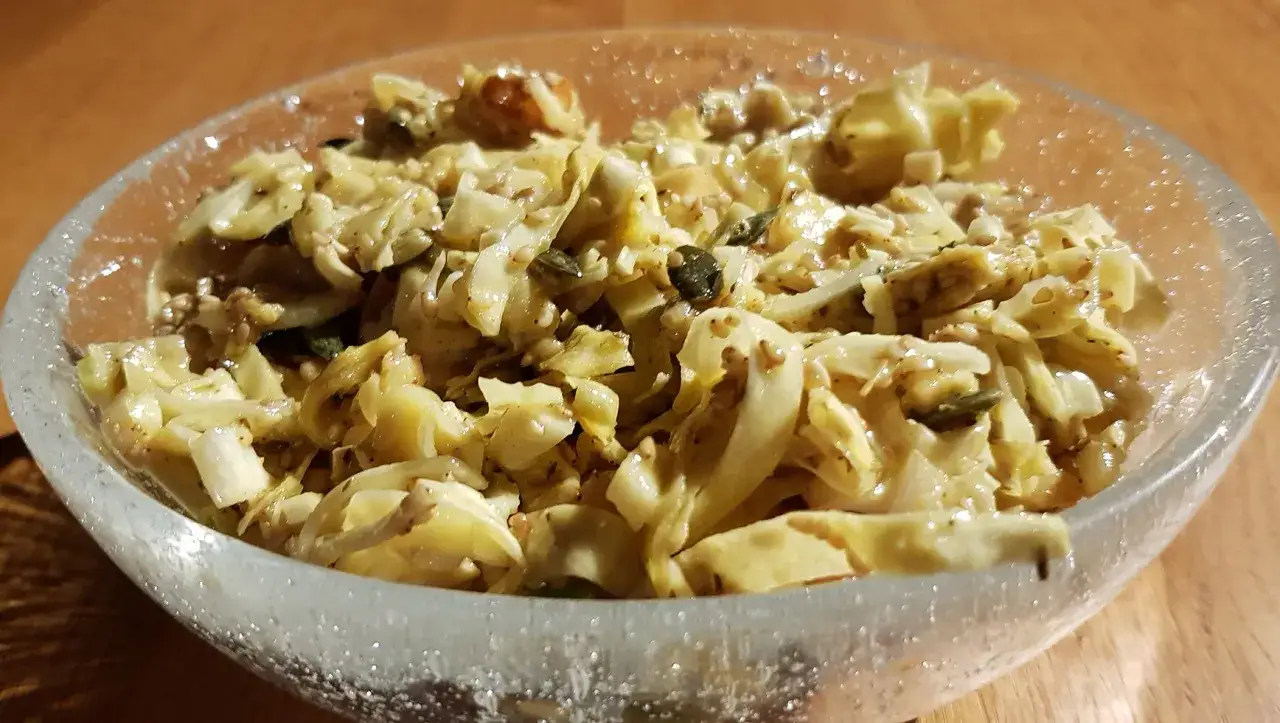 Ein köstlicher spitzkohl salat mit Kürbiskernen und Sesam in einer Glasschüssel, bereit zum Genießen.