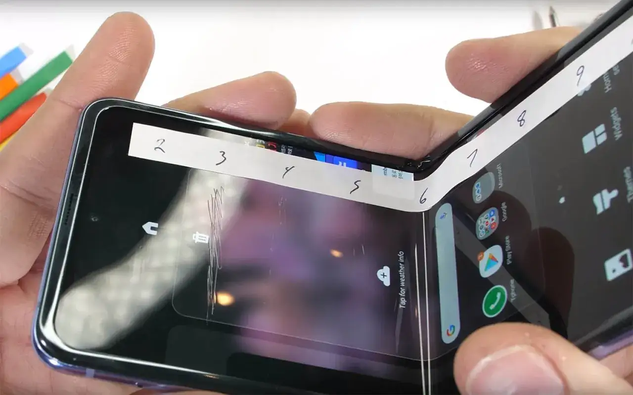 Złożony smartfon z ekranem chronionym przez Gorilla Glass Victus 2, z widocznymi numerami na taśmie testowej.