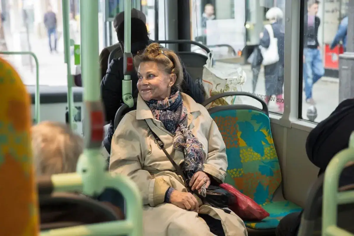 Une femme âgée profite du transport gratuit pour personne âgée, souriante dans le bus.