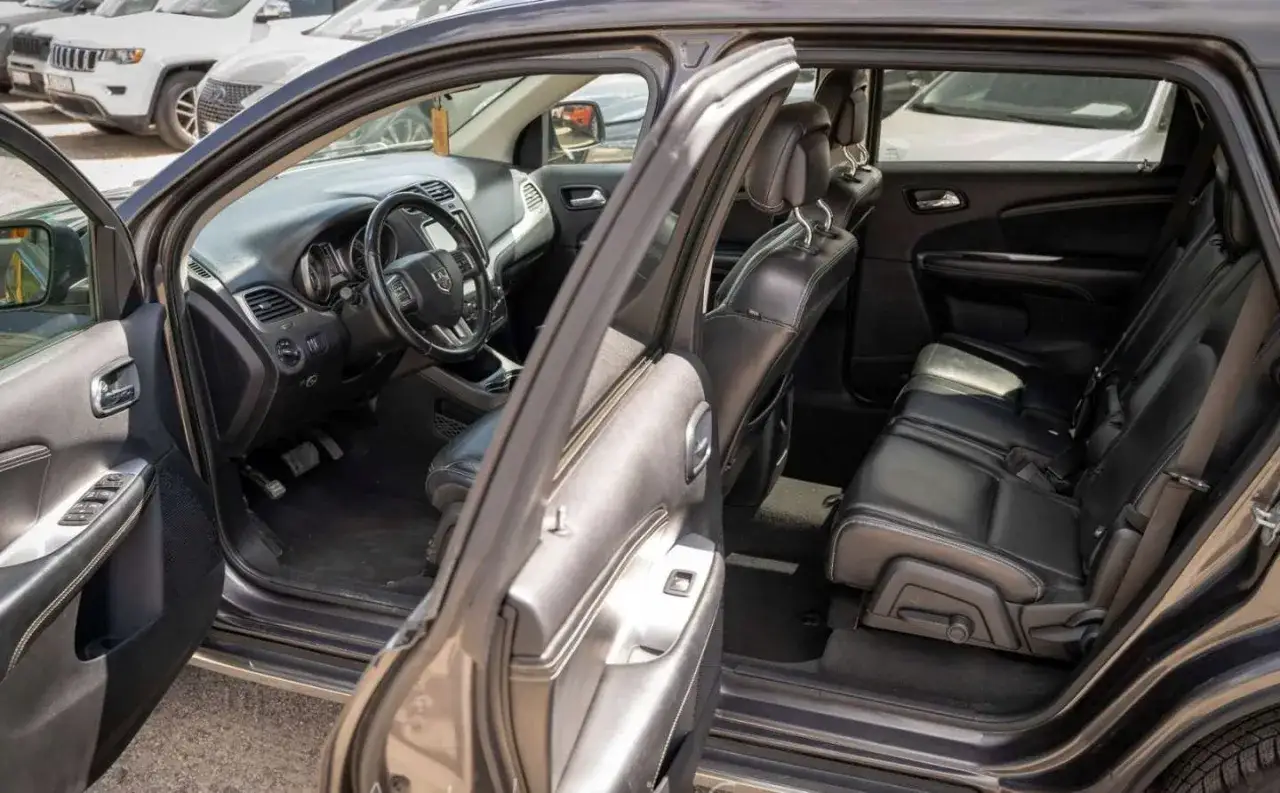Wnętrze Dodge Journey 3.6 z czarną skórzaną tapicerką i widocznym kokpitem.