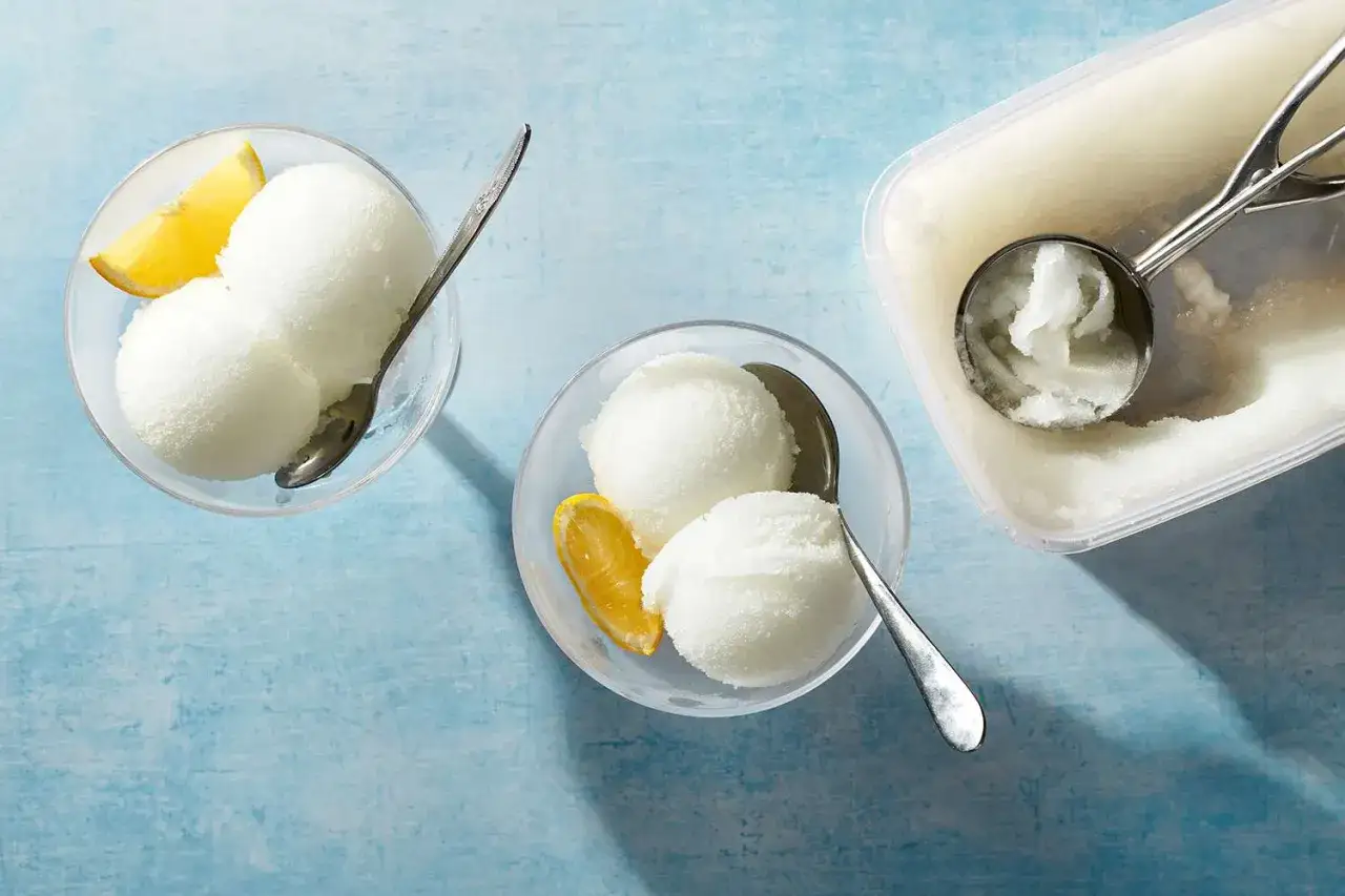 Deux coupes de sorbet citron, garnies d'une tranche d'orange, prêtes à être dégustées. Un colonel dessert parfait pour se rafraîchir.