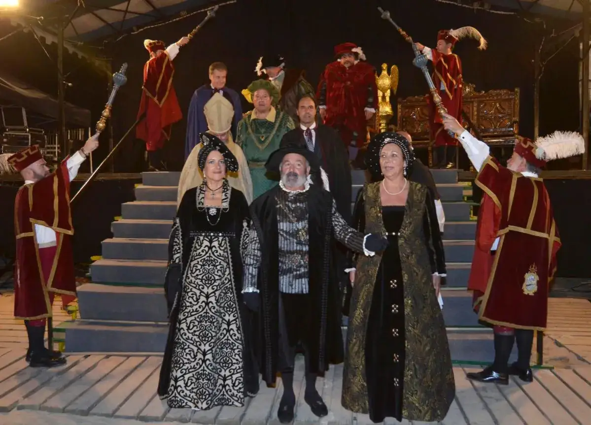 Recreación del desembarco de Carlos V en Laredo. Personajes con trajes de época, algunos portando cetros, posan en unas escaleras.