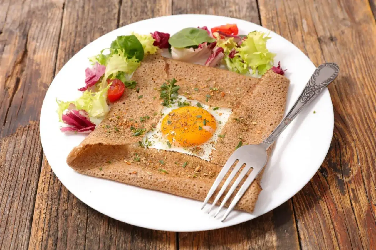 Une d&eacute;licieuse cr&ecirc;pe compl&egrave;te bretonne avec un &oelig;uf au plat, herbes et une salade fra&icirc;che. Un plat savoureux pour un repas authentique.