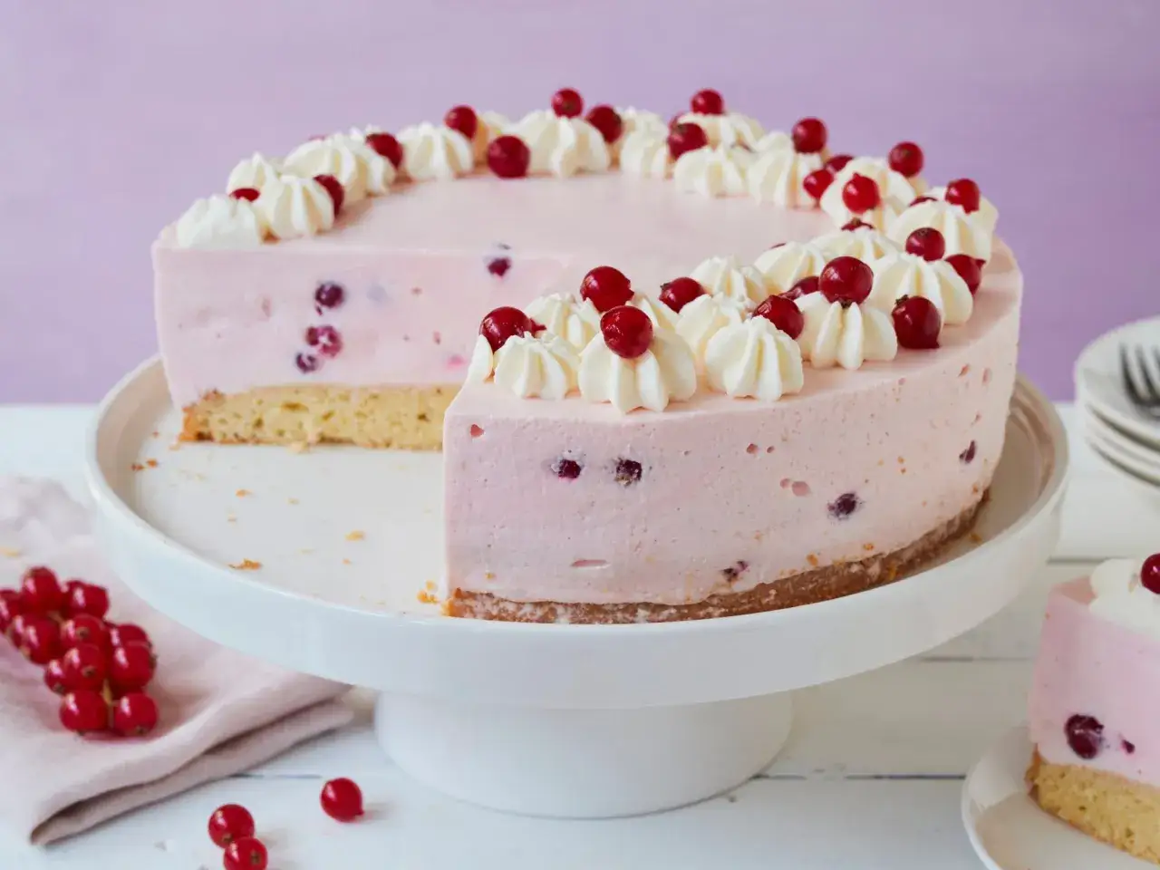 Leckere Johannisbeertorte mit Joghurt, verziert mit Sahnetuffs und frischen Johannisbeeren.