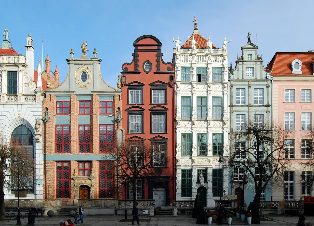 Kolorowe kamienice na Rynku w Gdańsku, z bogatymi zdobieniami i charakterystycznymi fasadami.