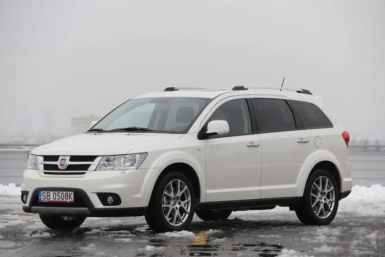 Biały Fiat Freemont na śniegu. Zastanawiasz się nad jego spalaniem? Ten rodzinny SUV oferuje przestronne wnętrze i komfort jazdy.
