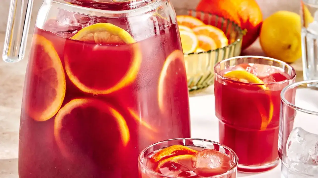 Carafe et verres remplis d'une sangria fruit&eacute;e avec des rondelles d'orange et de citron. Une recette rafra&icirc;chissante pour l'&eacute;t&eacute;.